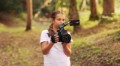 Cute girl walking in the forest and shooting a video using a professional video camera